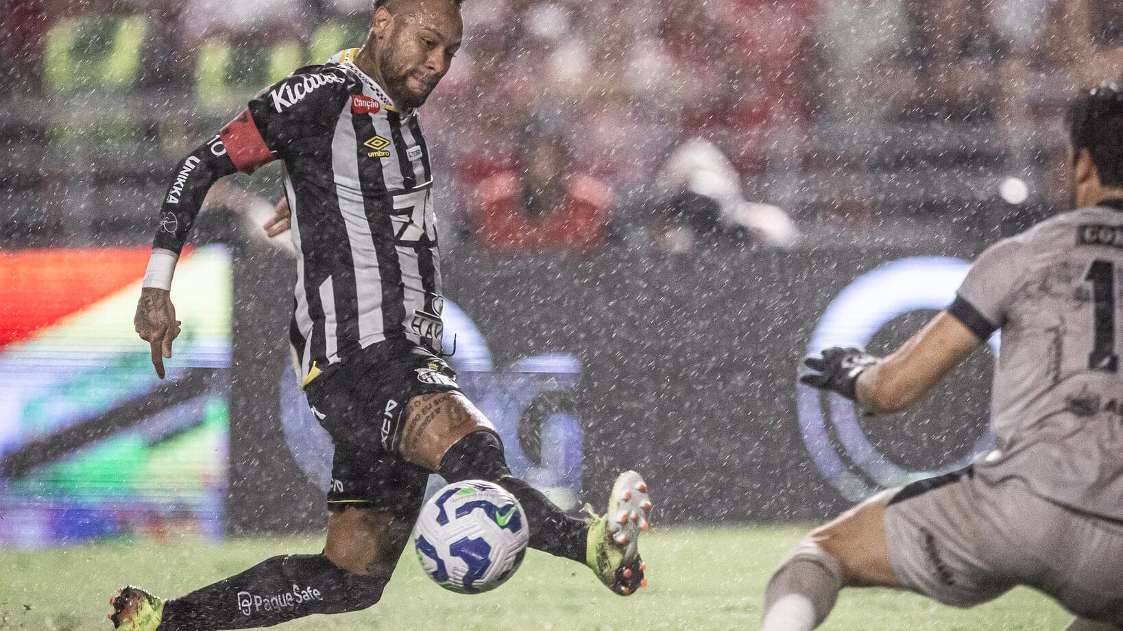 Neymar estica a perna direita e tenta chutar a bola enquanto o goleiro do CRB tenta fazer a defesa